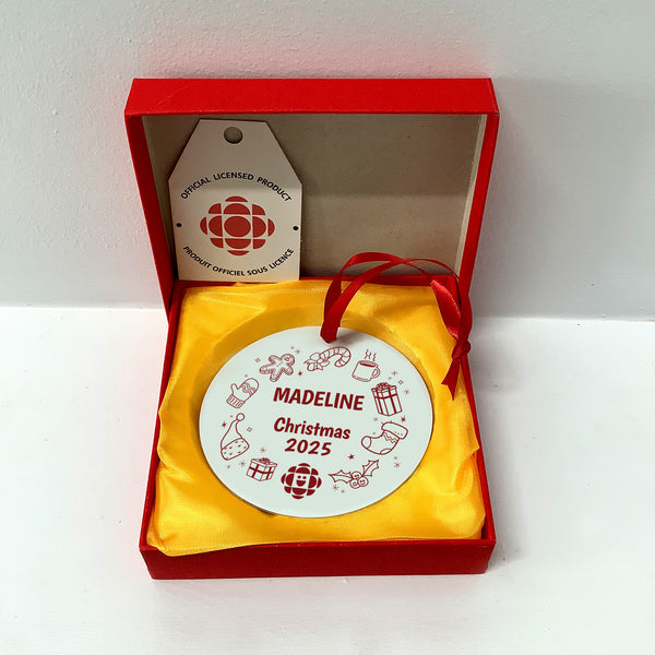 Christmas ornament with 'Madeleine Christmas 2025' text in a red box with yellow interior